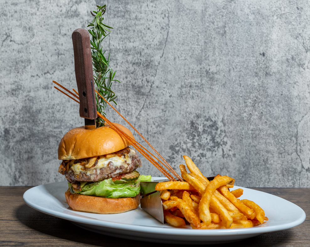 Hash House A Go Go Twisted Burger with melted cheese, lettuce, and crispy fries at Orlando International Drive.
