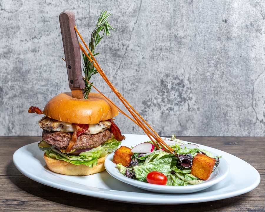 Twisted Burger with bacon, cheese, and fresh toppings served with a side salad at Hash House A Go Go Orlando on International Drive – a bold lunch favorite.